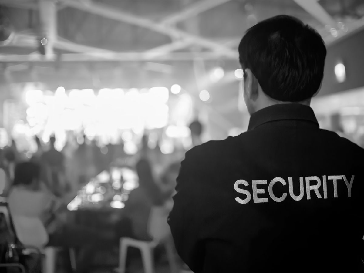Security guard monitoring a crowd at a large indoor event to maintain crowd control and guest safety