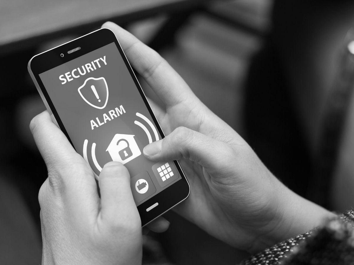 Person using mobile phone security app to manage alarm system and prevent false alarms