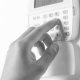 Person arming a business alarm system by pressing a code on a security keypad mounted on a wall