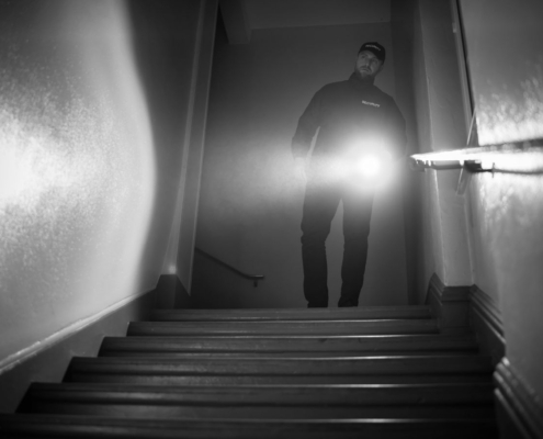 Security guard carrying out a mobile patrol inspection inside a building stairwell at night