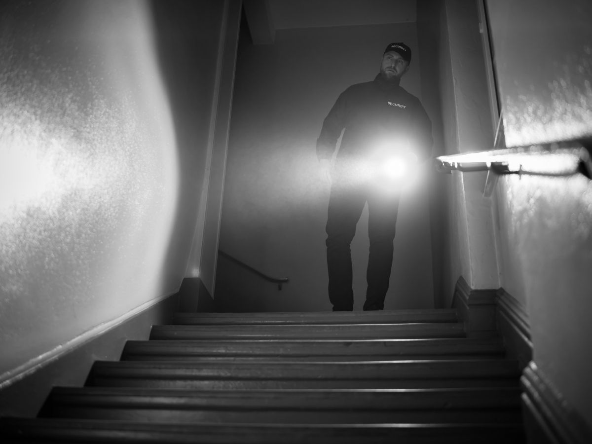 Security guard carrying out a mobile patrol inspection inside a building stairwell at night
