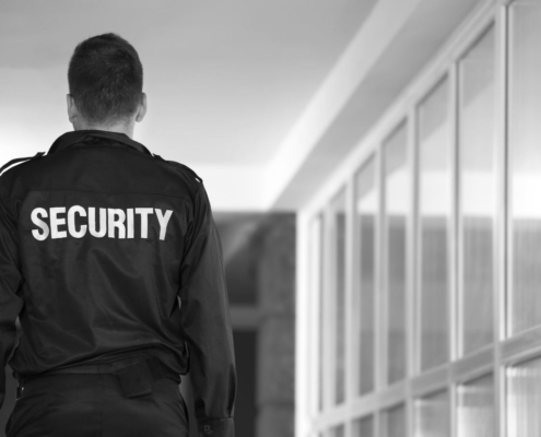 Security guard standing outside a commercial building during an after hours security patrol, monitoring and protecting business premises.
